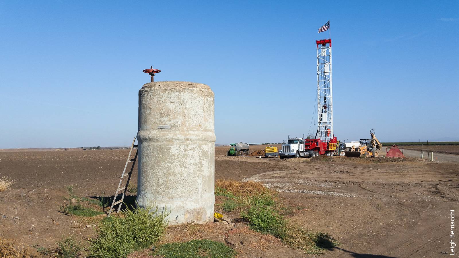 A rig drills a new well in Merced County. In the foreground is a pressure relief structure for subsurface water pipes.