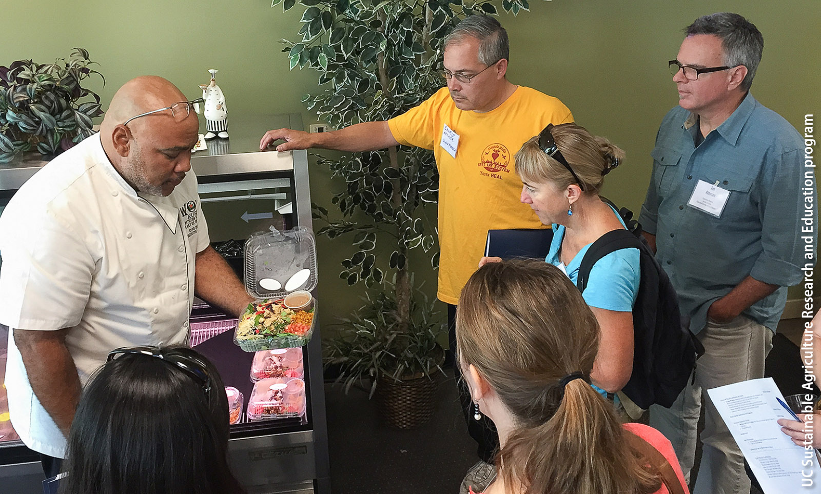 On an educational tour for elected officials and government staff, a food service director explains the contents of a grab-and-go salad for students.