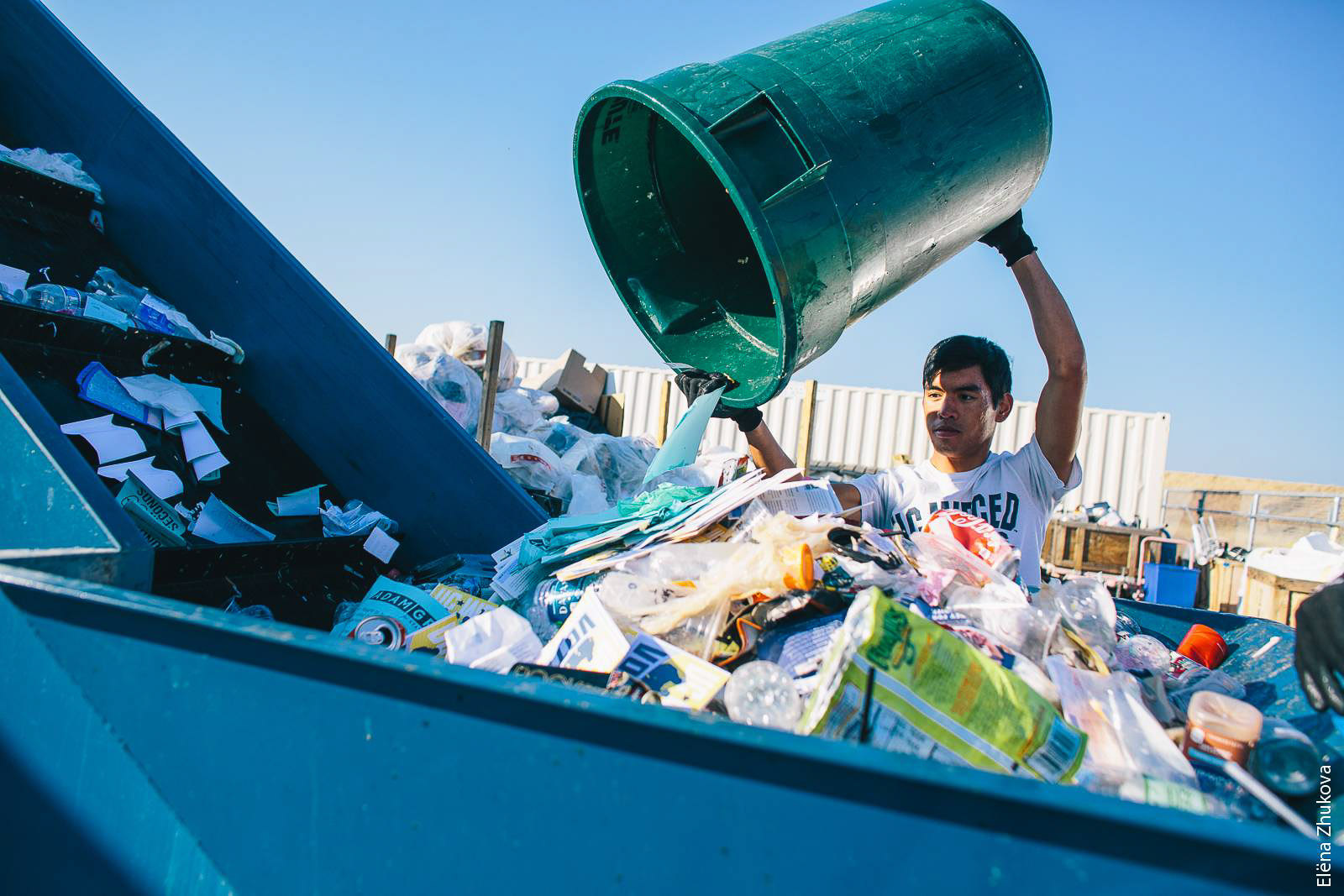 UC Merced student Andrew De Los Santos empties a campus waste bin into a hopper. A conveyor belt carries the materials to a sorting line for separation into recycling, compost and landfill channels.