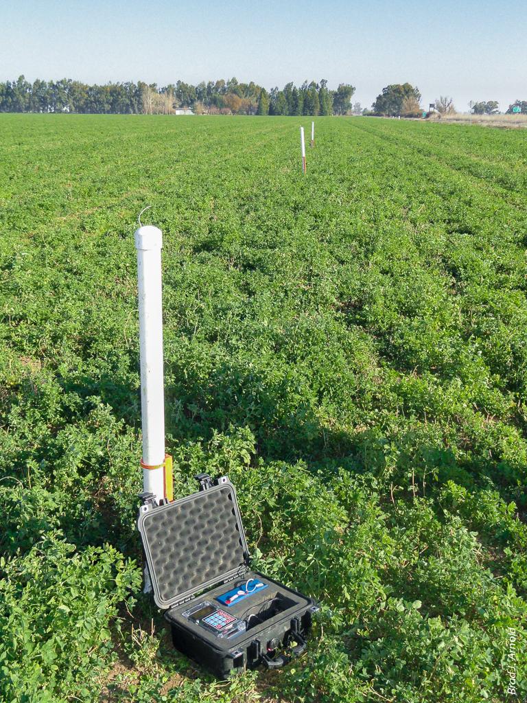 When a sensor (white pole) detects water arrival, a wireless signal is sent to the central module (black box), which generates a text message alert to the irrigator.